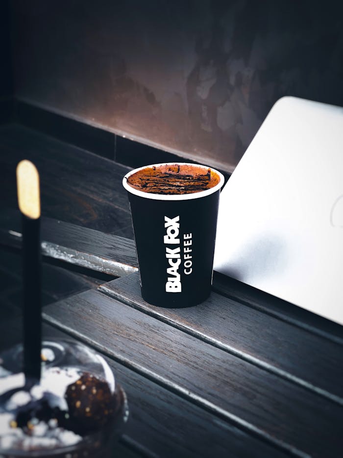 A chic coffee cup from Black Box Coffee placed on a wooden table in a cafe setting.