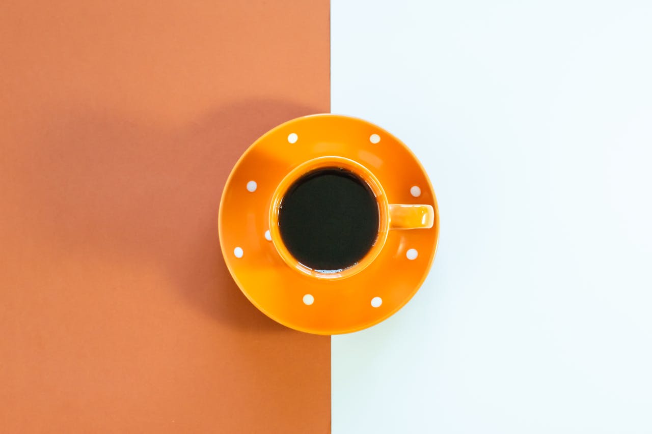 Stylish bright orange coffee cup on a minimalist orange and white backdrop.